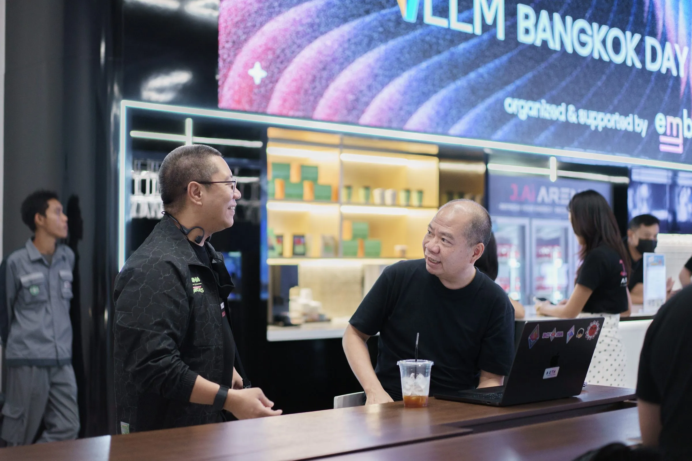 Attendees at the lounge counter under the vLLM Bangkok Day banner